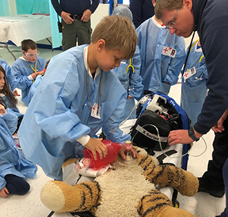 Elementary student learning CPR on a teddy bear
