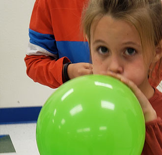 Student blowing a green balloon